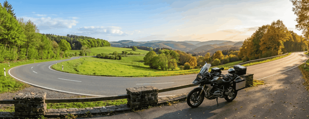 Motor geparkeerd bij een uitzichtpunt in de Eifel met frisgroene voorjaarskleuren en warme herfsttinten langs een bochtige weg